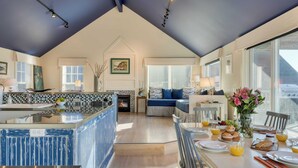 Een ruime keuken met een groot eiland, een eethoek met ontbijtgedeelte, en een gezellige woonkamer met een bank en een open haard.