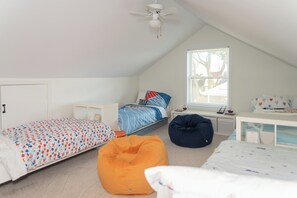 Ein Schlafzimmer mit Bett, Sitzsack, Schreibtisch, Fenster und Deckenventilator.