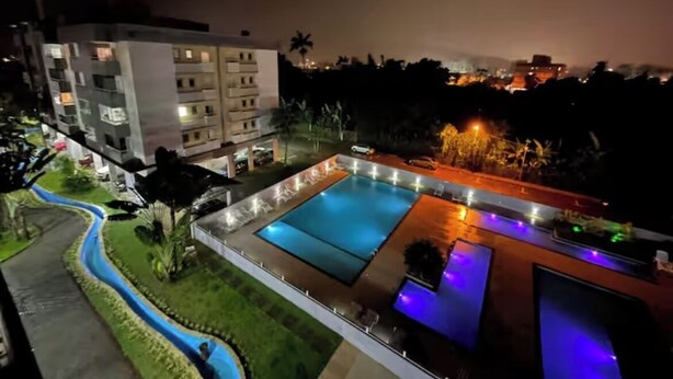 A nighttime view of a hotel with a swimming pool, a landscaped garden, and a modern building with illuminated balconies. - Beautiful, cozy apartment in Pereque Açu, Passaredo, Ubatuba. (Ubatuba)