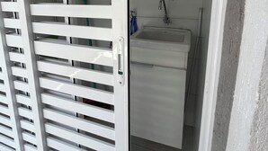 A white room with a white door, a white sink, and a white cabinet. - Beautiful, cozy apartment in Pereque Açu, Passaredo, Ubatuba. (Ubatuba)