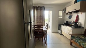 A compact kitchen with a refrigerator, dining table, chairs, and a small sofa. - Beautiful, cozy apartment in Pereque Açu, Passaredo, Ubatuba. (Ubatuba)