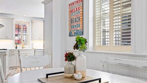 Een moderne keuken met witte kasten, een eettafel met dienblad en een decoratief wandobject.