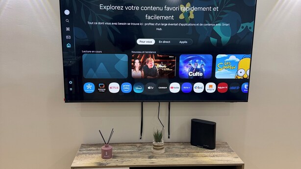 A flat-screen TV mounted on a wall with a wooden console below.