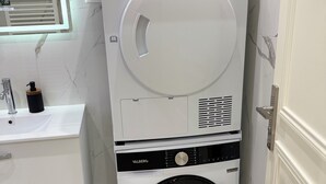 A compact, modern laundry room with a built-in washer and dryer, a small sink, and a mirror above the sink.