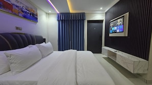 Ein modernes Hotelzimmer mit einem großen Bett, einem flachbildfernseher an der Wand und einer dunkel gefärbten Tür.