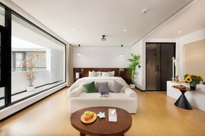 A modern hotel room with a large bed, a sofa, a dining table, and a large window. - Shangri La cuckoo homestay (Deqin)