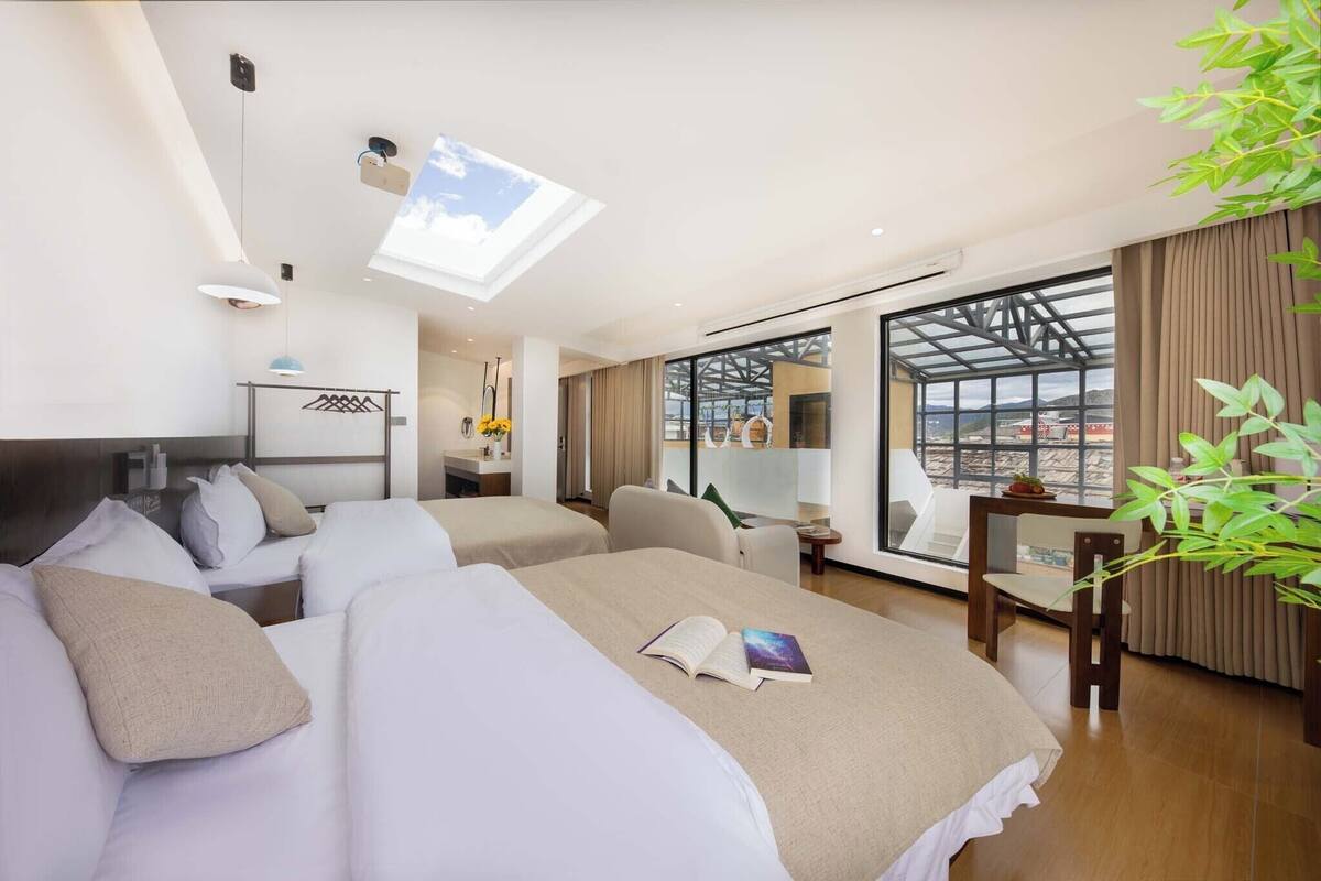 Een moderne hotelkamer met een groot bed, een bureau en uitzicht op de stad door grote ramen.