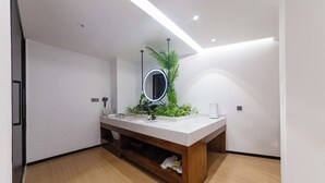 Une salle de bain moderne avec un meuble-lavabo blanc, une étagère intégrée, un miroir à cadre circulaire et une plante en pot.