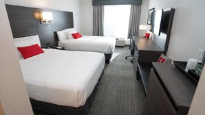 Une chambre d’hôtel avec deux lits, un bureau, une chaise, une télévision et une fenêtre avec des rideaux.