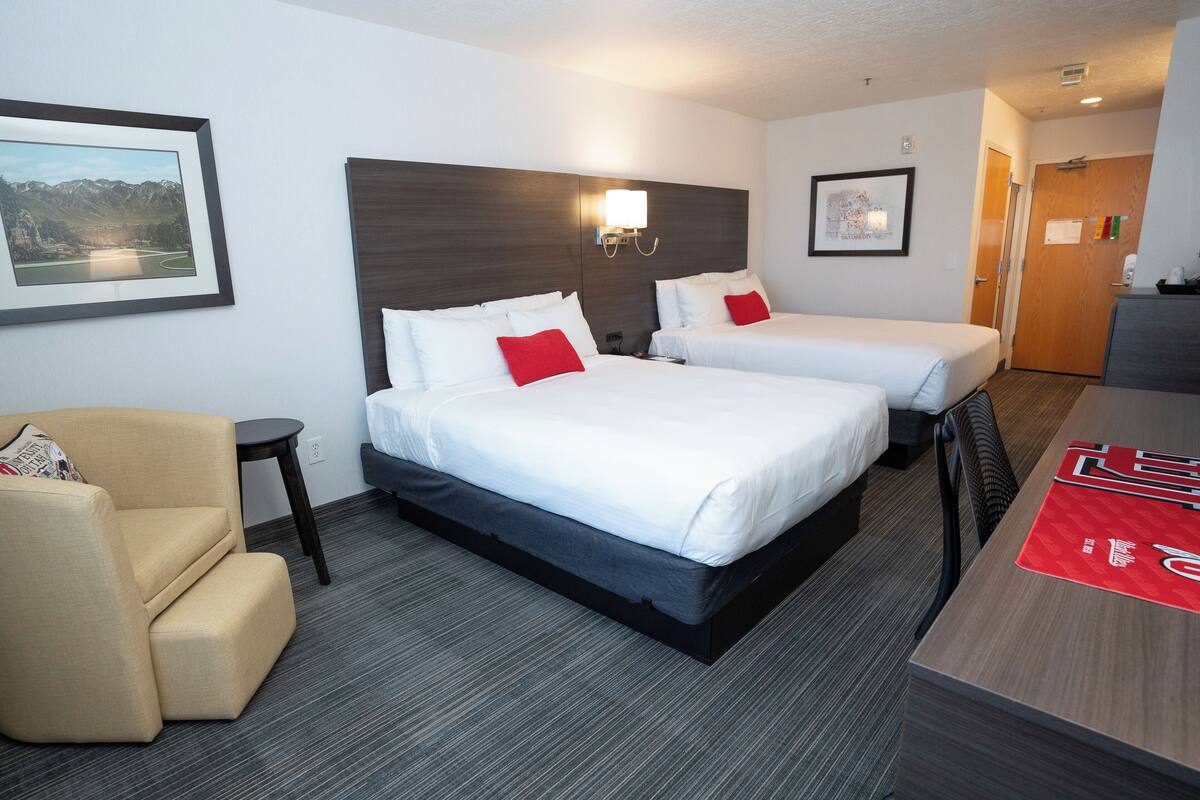 Een hotelkamer met twee bedden, een bank, een bureau en uitzicht op bergen.