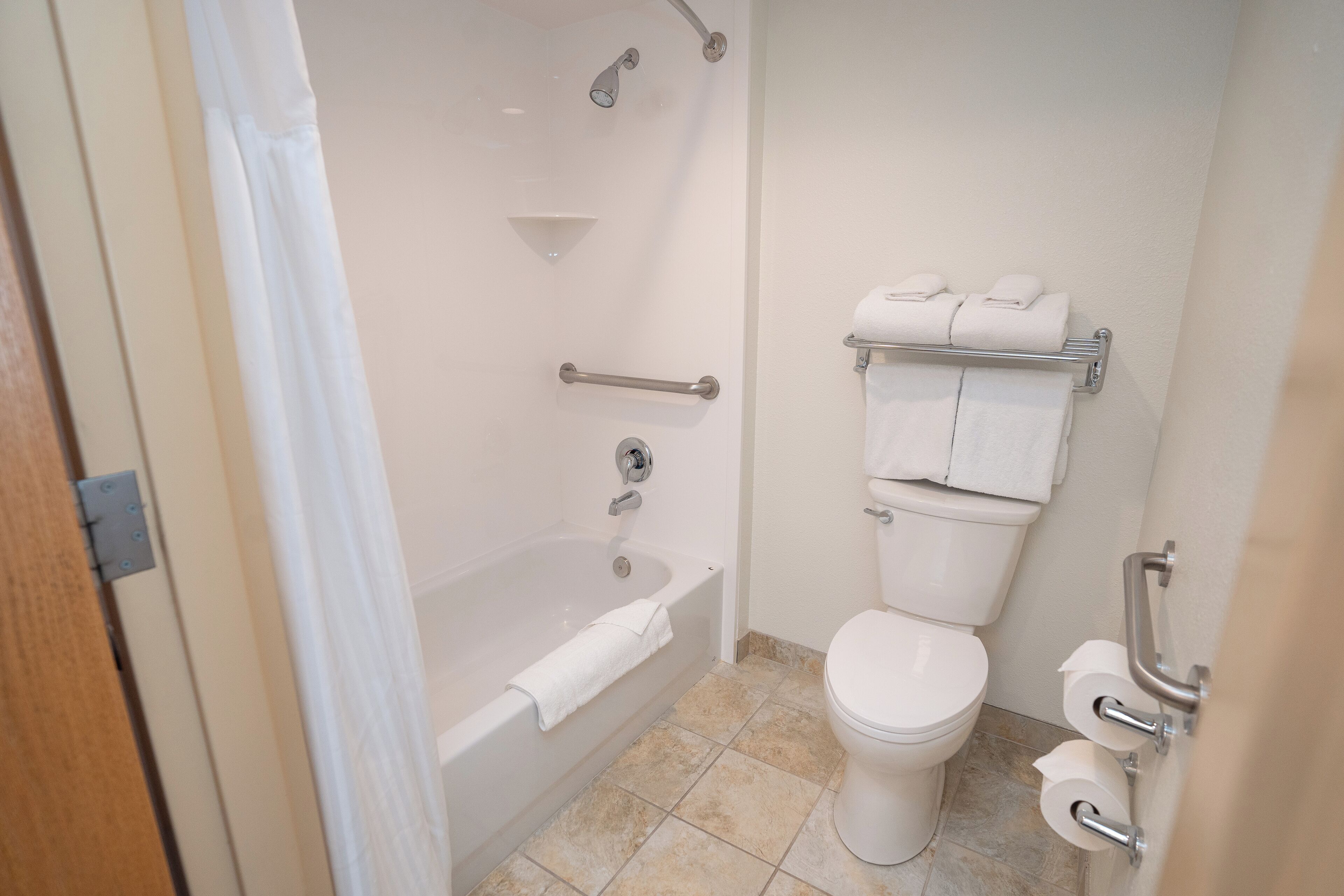 Ein Badezimmer mit Badewanne, Toilette und Haltegriffen.