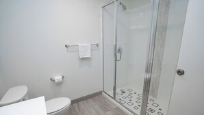 Une salle de bain moderne équipée de toilettes, d’une douche à parois de verre et d’un porte-serviettes.