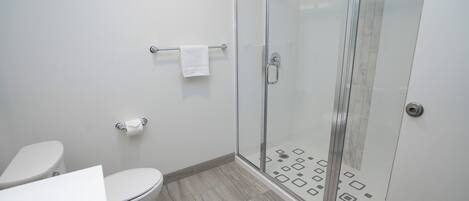 Un baño moderno con inodoro, cabina de ducha de vidrio y barra para toallas.