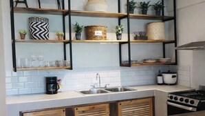 A kitchen with white tiled backsplash, wooden cabinets, a coffee machine, a sink, and a stove. - Las Naveiras 5 (Tamarindo)