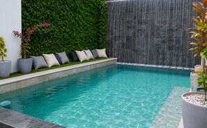A swimming pool with a waterfall feature, a green wall, and a seating area with cushions. - Las Naveiras 5 (Tamarindo)