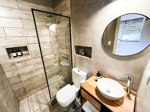 Ein modernes Badezimmer mit einer Duschkabine, einer Toilette und einem Waschtisch mit Waschbecken und Spiegel.