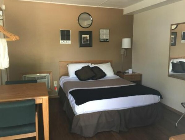 A hotel room with a bed, bedside table, lamp, and wall decorations including a mirror and framed pictures.