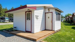 A small, single-story building with a red door and a sign indicating a washroom, shower, and laundry. - THE VICTORIAN MOTEL AND RV PARK by Capital O (Grand Forks)