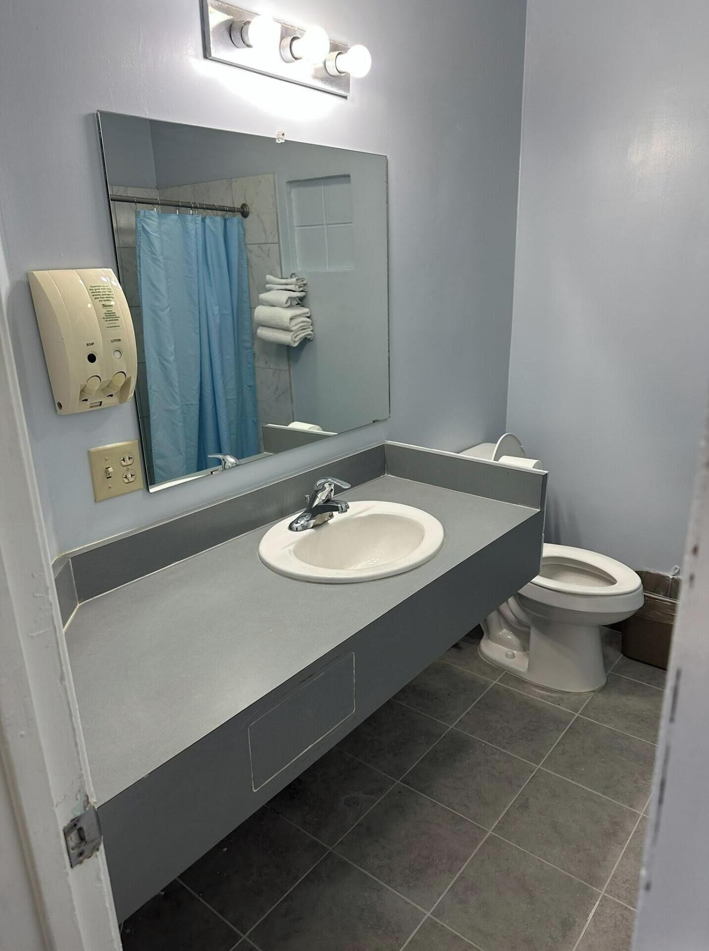 Un baño con lavamanos, espejo e inodoro.