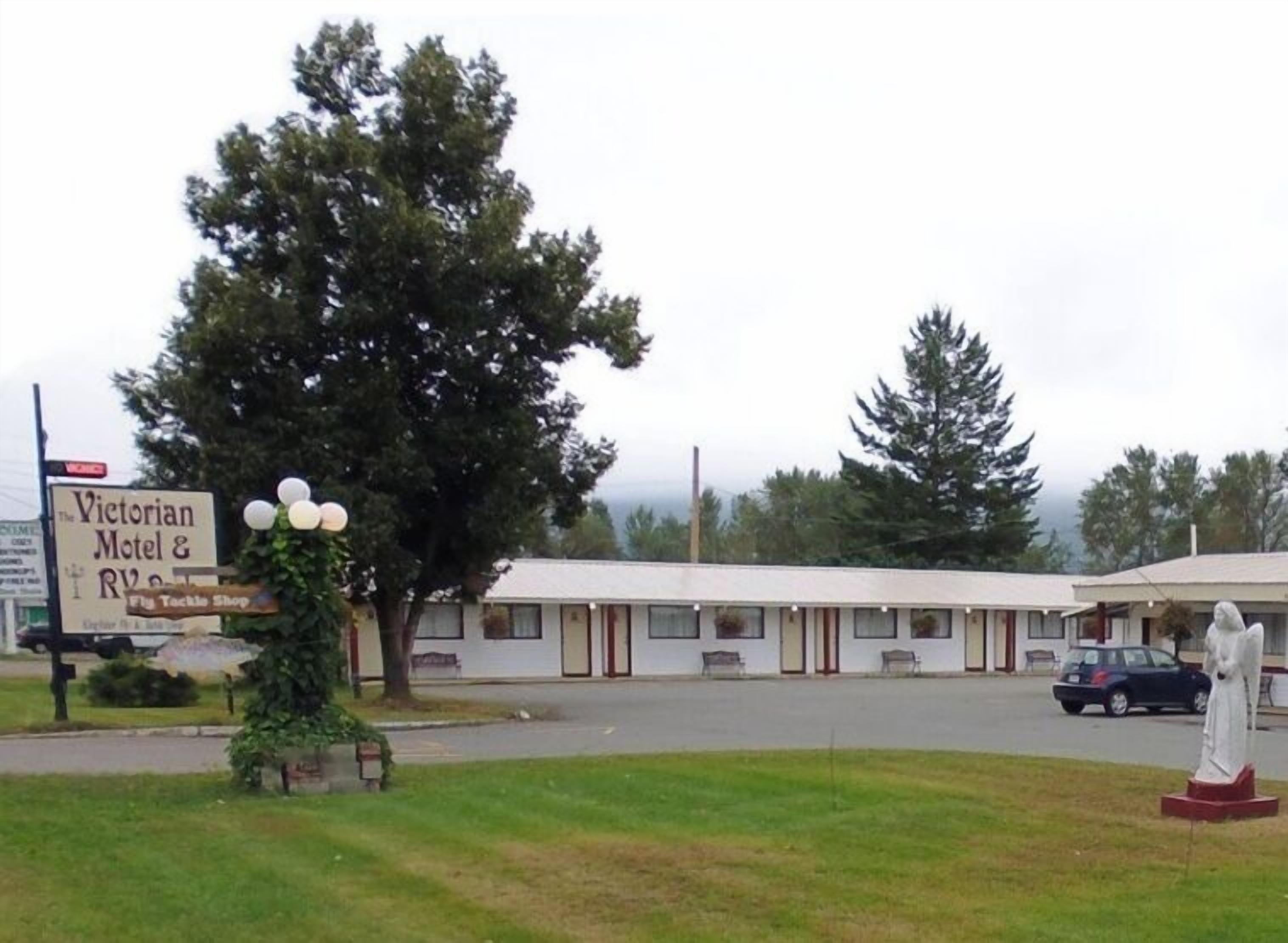 Un motel de style victorien, avec une rangée de bâtiments d’un seul étage, une statue et une enseigne indiquant la présence d’un magasin de pêche à la mouche.