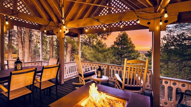 Une terrasse extérieure avec des meubles en bois, un foyer et des guirlandes lumineuses.