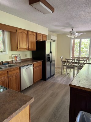 A modern kitchen with wooden cabinets, a stainless steel refrigerator, and a dishwasher. - Charming 4-bedroom cabin in Maggie Valley (Maggie Valley)