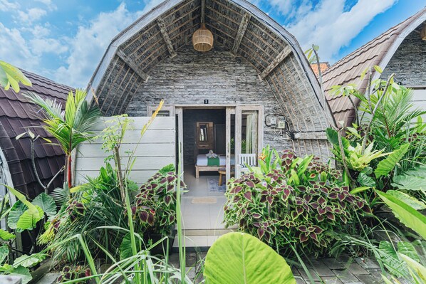 A rustic wooden house with a sloped roof and a small porch. - Sunshine Village Canggu (Tibubeneng)