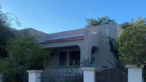 Una casa residenziale con cancello, tetto in tegole e vialetto in cemento.