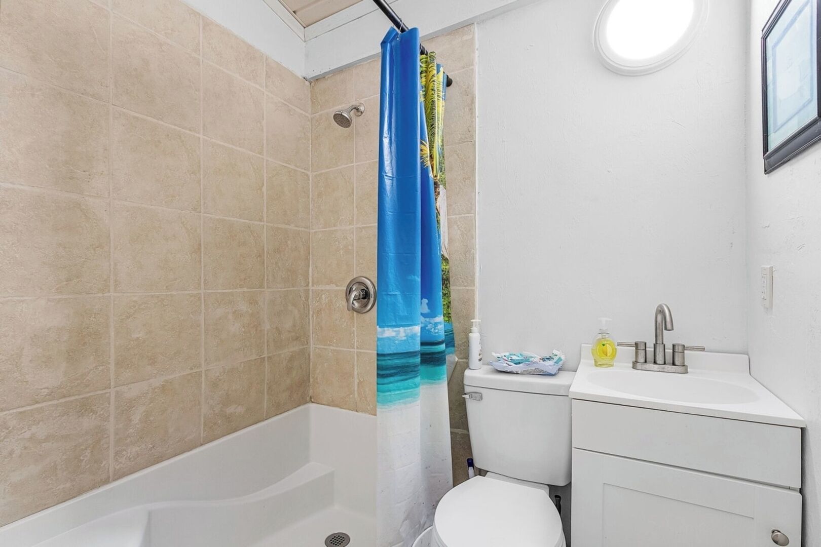 Une salle de bain avec des carreaux de couleur beige, une baignoire, des toilettes et un lavabo avec un miroir.