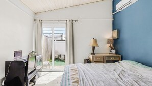 A bedroom with a bed, a desk with a laptop, a lamp, and a small table with decorative items. - Pet-Friendly • Outdoor Space + Parking (Cape Coral)
