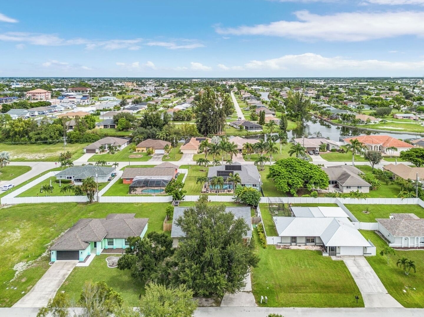 A residential area with houses, green lawns, and a clear sky.