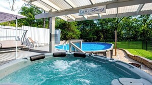 A hot tub with a sign above it, a pool, and a covered patio area. - CLT Oasis (Charlotte)