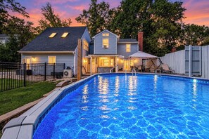A residential swimming pool with a house in the background.