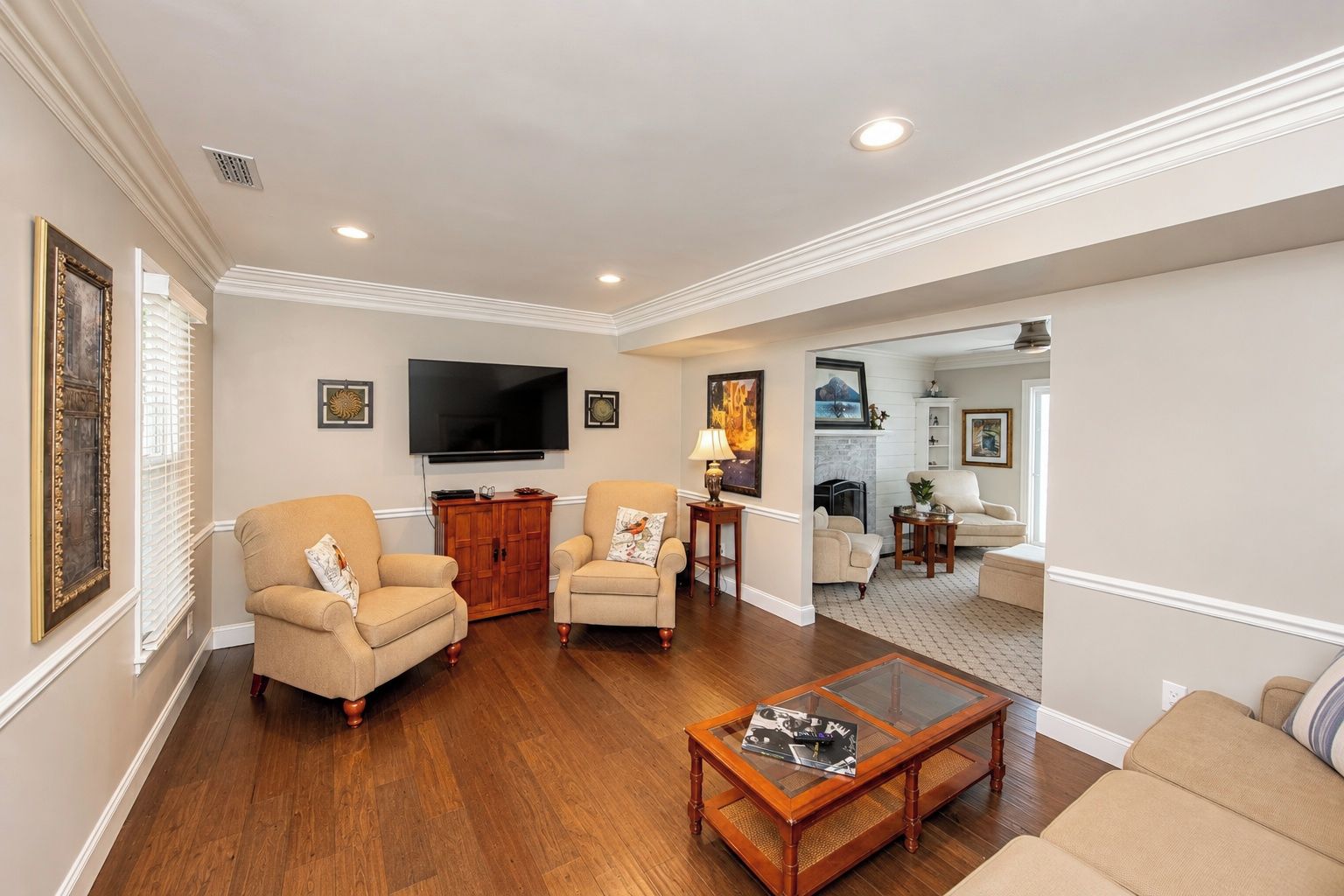 A living room with two armchairs, a coffee table, a flat-screen TV, and a fireplace.
