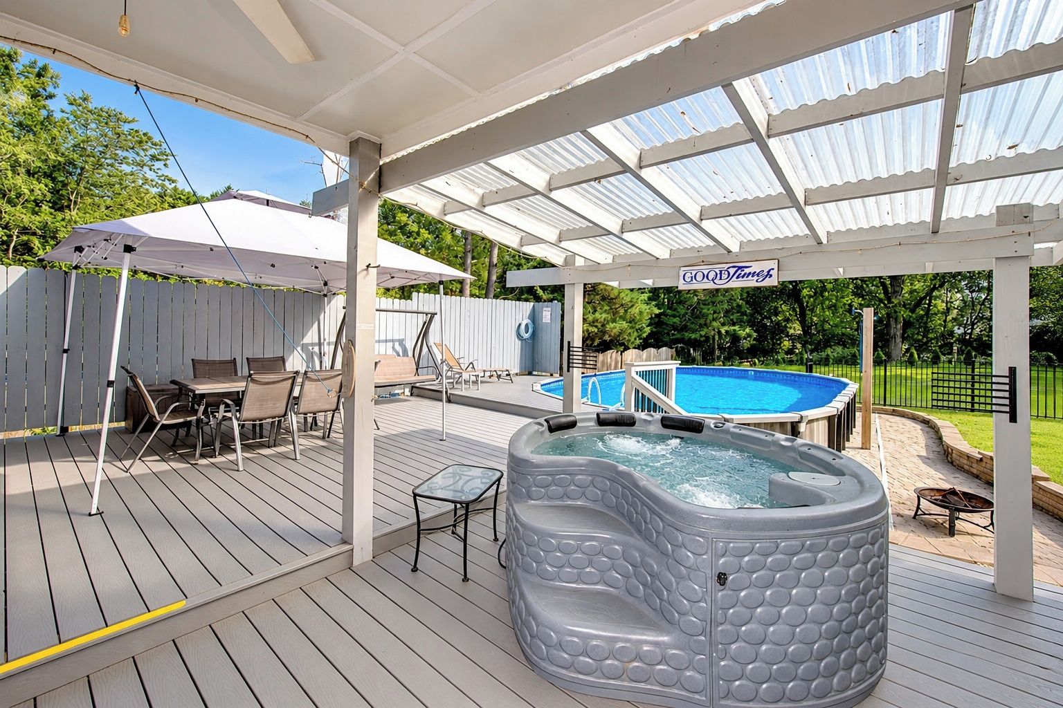 Eine überdachte Terrasse im Freien mit Whirlpool, Pool und einer Liegefläche mit Stühlen und Tischen.