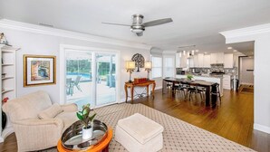 A spacious living room with a large window, a dining area, and a kitchen. - CLT Oasis (Charlotte)