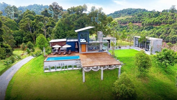 Una casa moderna con piscina, terraza y vistas a un paisaje verde exuberante.