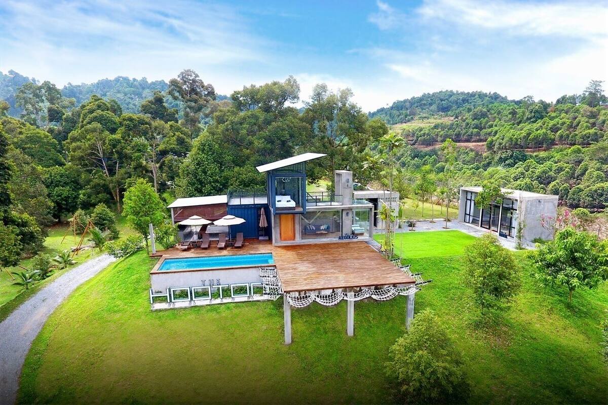 Een modern huis met een zwembad, een terras en uitzicht op een weelderig groen landschap.
