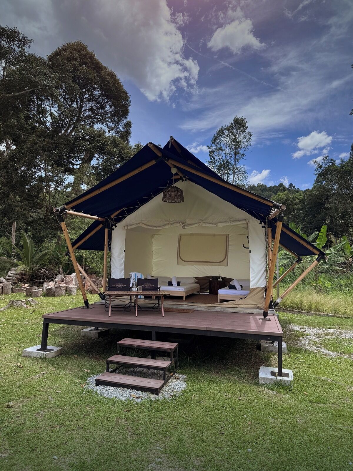 A tent with a flat roof, a small table, and a bench in a grassy area.