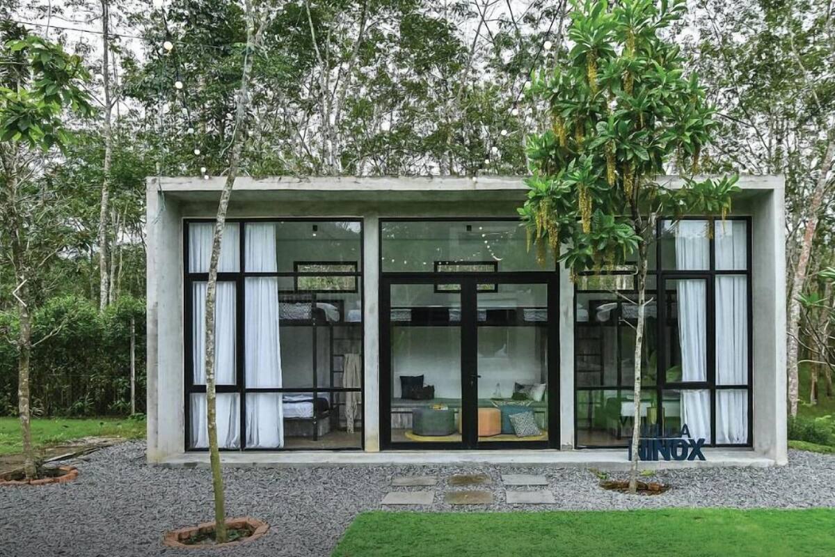 Een modern, laag gebouw met grote glazen deuren en ramen, gelegen in een natuurlijk, bebost gebied.