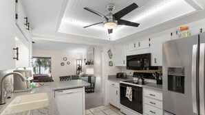 A modern kitchen with a built-in dishwasher, a microwave, a refrigerator, and a ceiling fan.