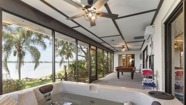 A spa area with a hot tub, a pool table, and a view of the lake.