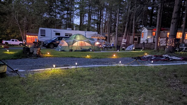 A campsite with tents, a trailer, and a small house. - RV-accessible cozy private campground with pool access near Lake Wallenpaupack (Hawley)