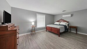 A bedroom with a bed, dresser, TV, lamp, and window. - Spacious Backyard • Fireplace • Mins from Downtown (Glasgow)