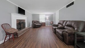 A living room with a fireplace, leather sofas, and a wooden floor. - Spacious Backyard • Fireplace • Mins from Downtown (Glasgow)
