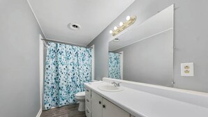 A bathroom with a white sink, mirror, and toilet. - Spacious Backyard • Fireplace • Mins from Downtown (Glasgow)