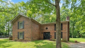 A two-story brick house with a front door, a small porch, and a tree in front. - Spacious Backyard • Fireplace • Mins from Downtown (Glasgow)