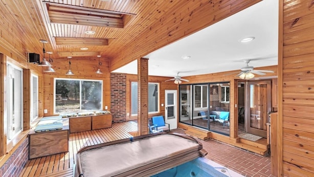 Une cabane en bois dotée d’un bain à remous, de grandes fenêtres et d’un espace patio.