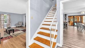 Un vaste espace de vie agrémenté d’un escalier en bois, un coin repas avec un mobilier moderne et une vue sur l’extérieur.
