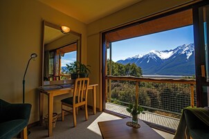 Una habitación con escritorio de madera, silla y un amplio ventanal con vista a la montaña.